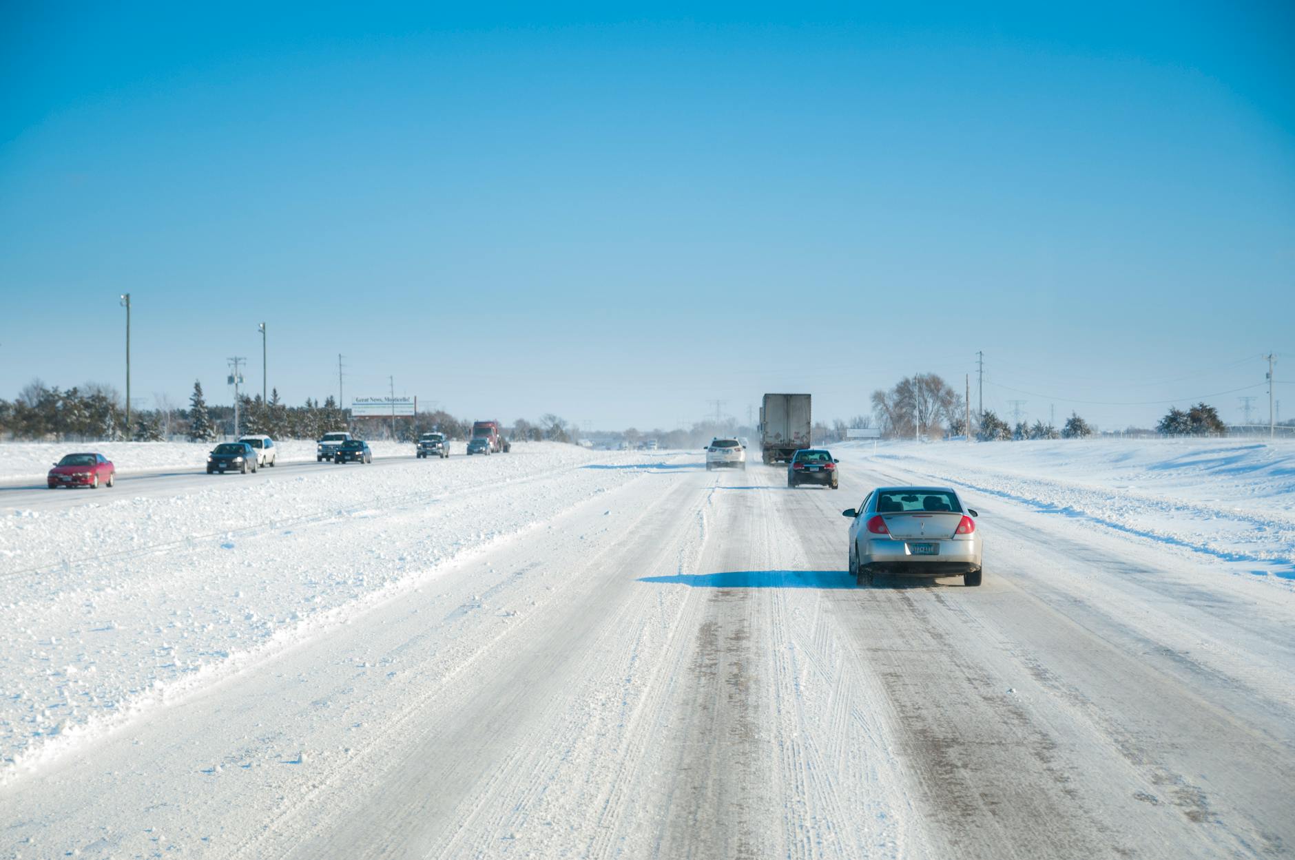Samochody jadą śnieżną drogą ekspresową S52 w słoneczny zimowy dzień