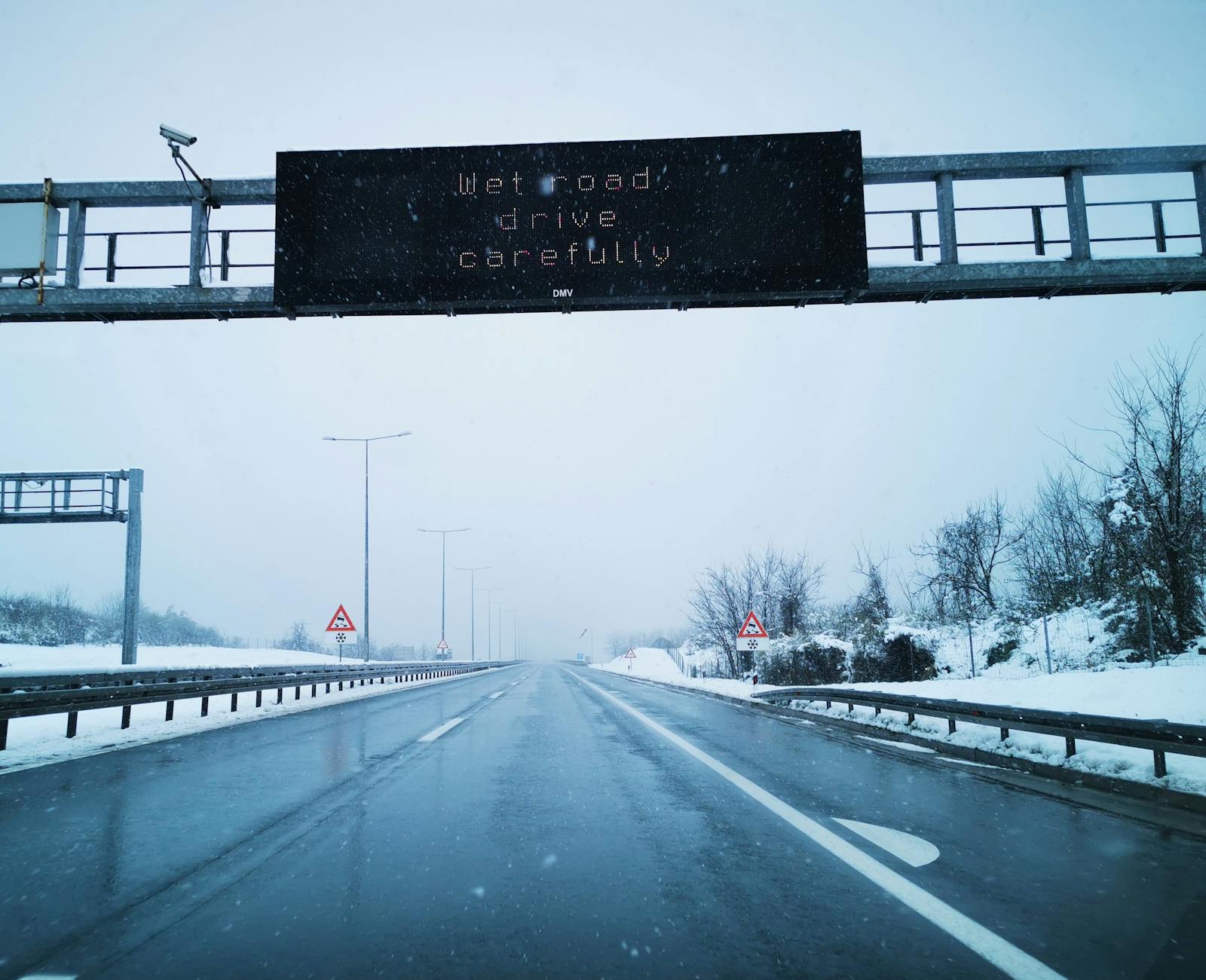 Zaśnieżona droga ekspresowa z ostrzegawczym znakiem w trakcie opadów