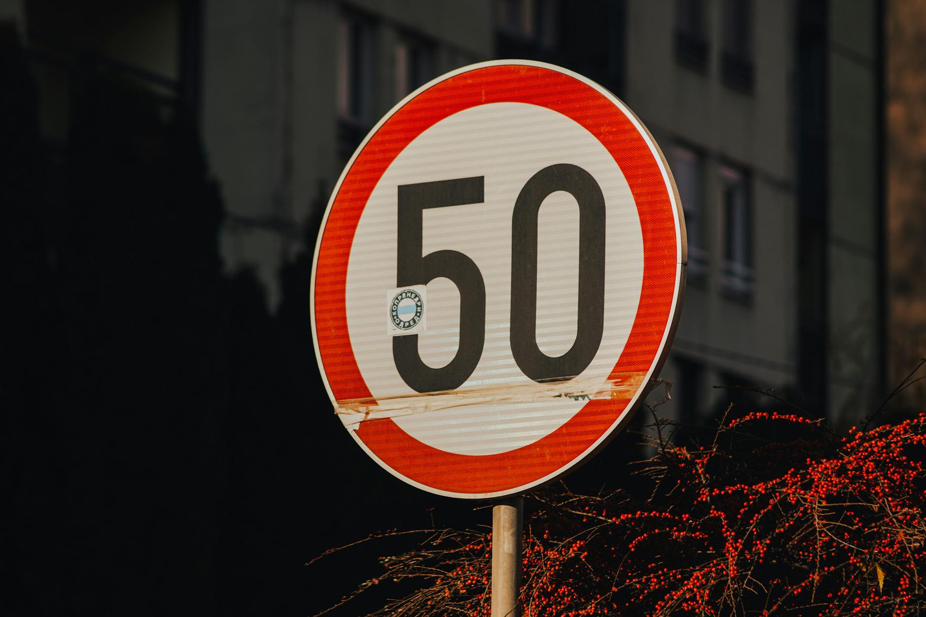 Znak ograniczenia prędkości 50 km/h na tle miejskiej zabudowy