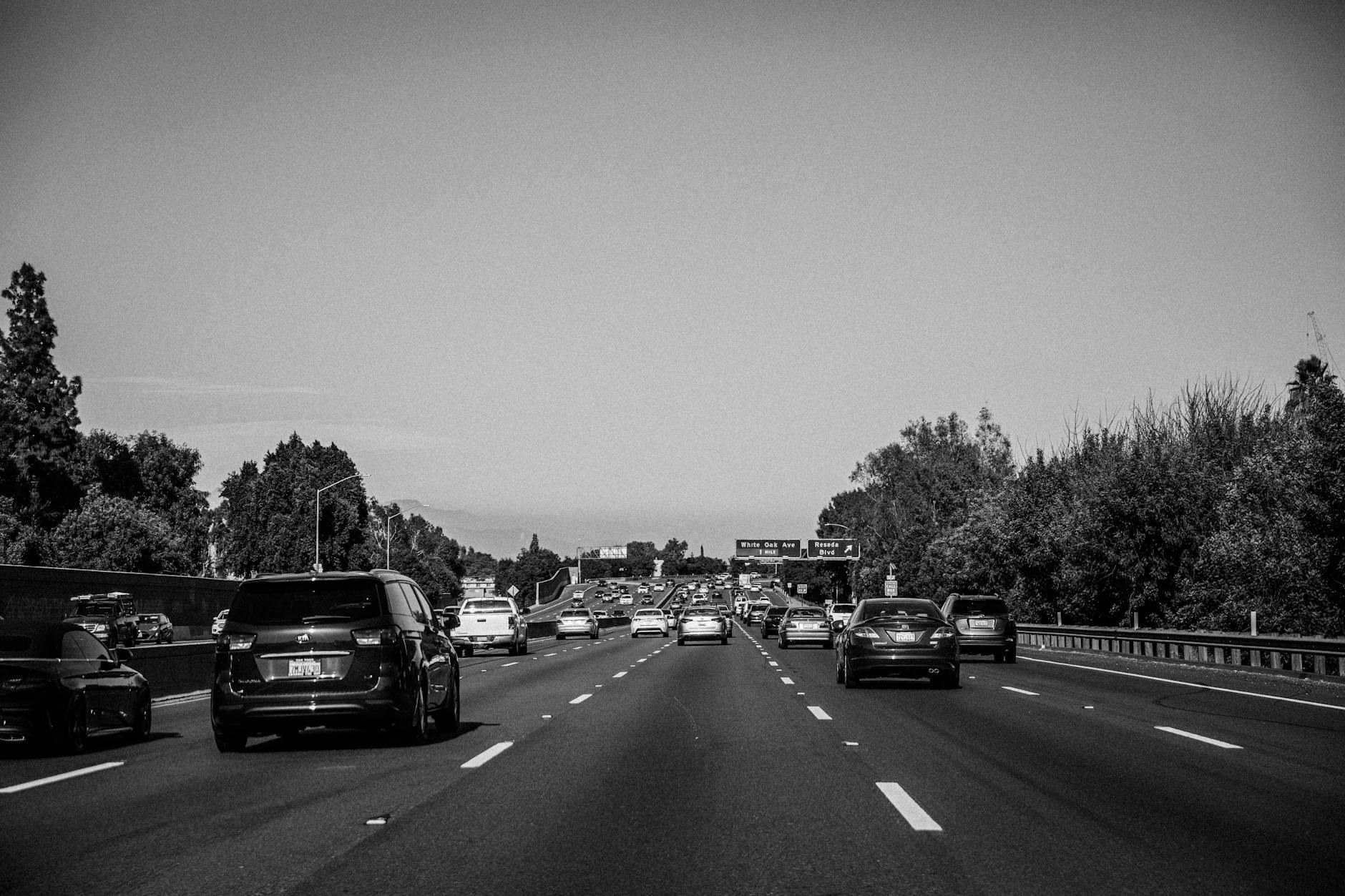 Czarnobiały korek na wielopasmowej autostradzie z tablicami kierunkowymi