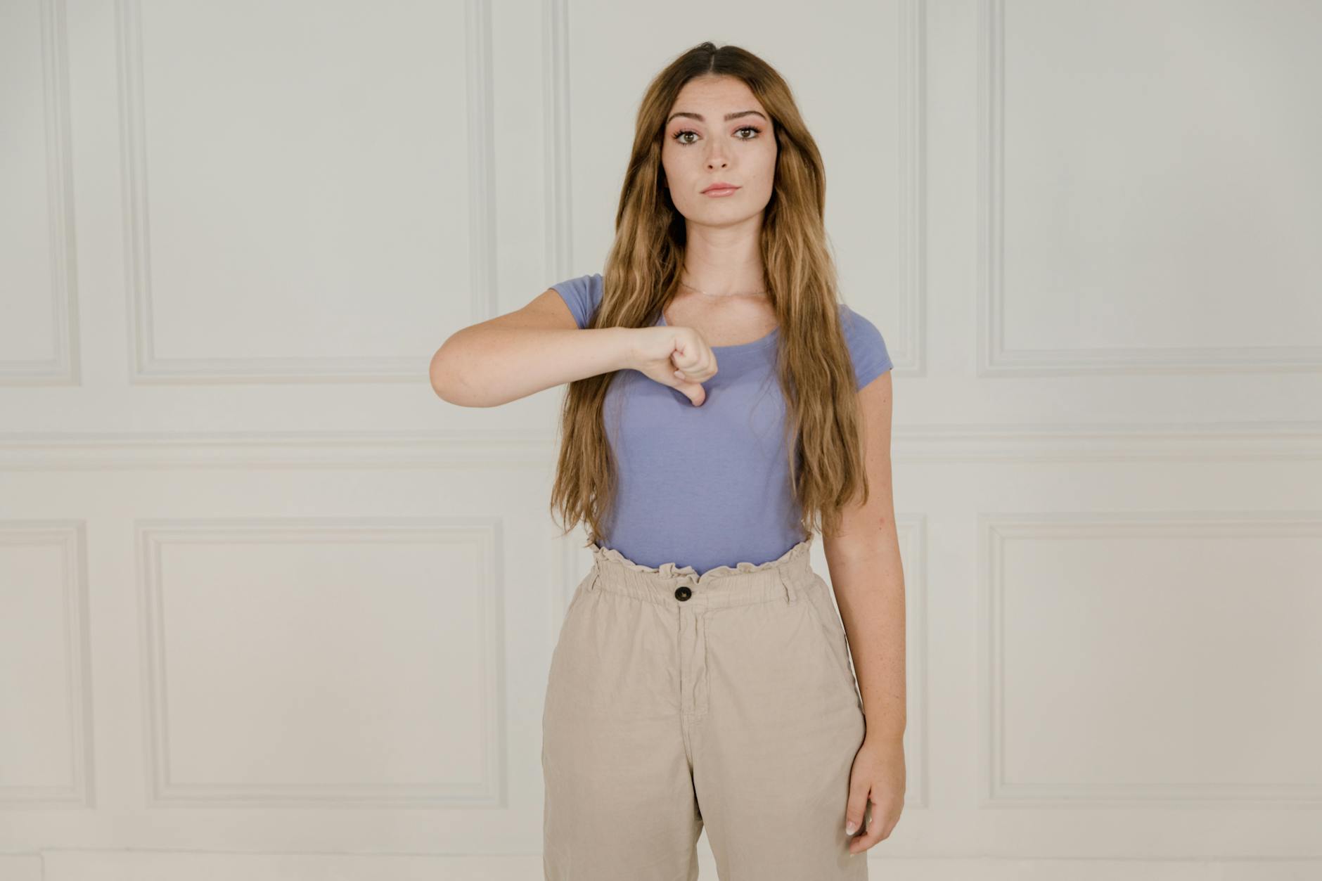 Młoda kobieta w pomieszczeniu pokazuje znaki języka migowego