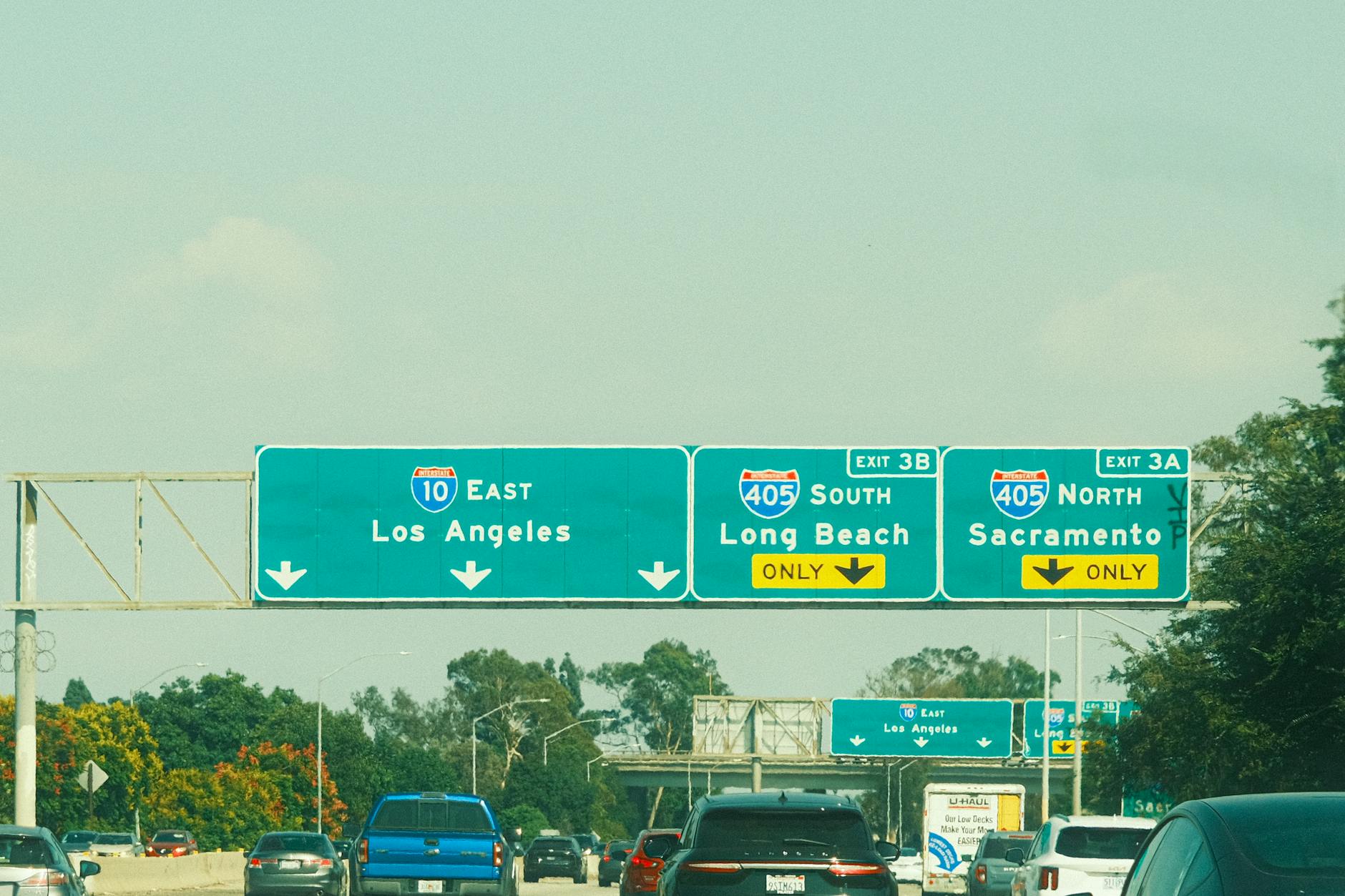 Zielone tablice kierunkowe nad autostradą w słoneczny dzień