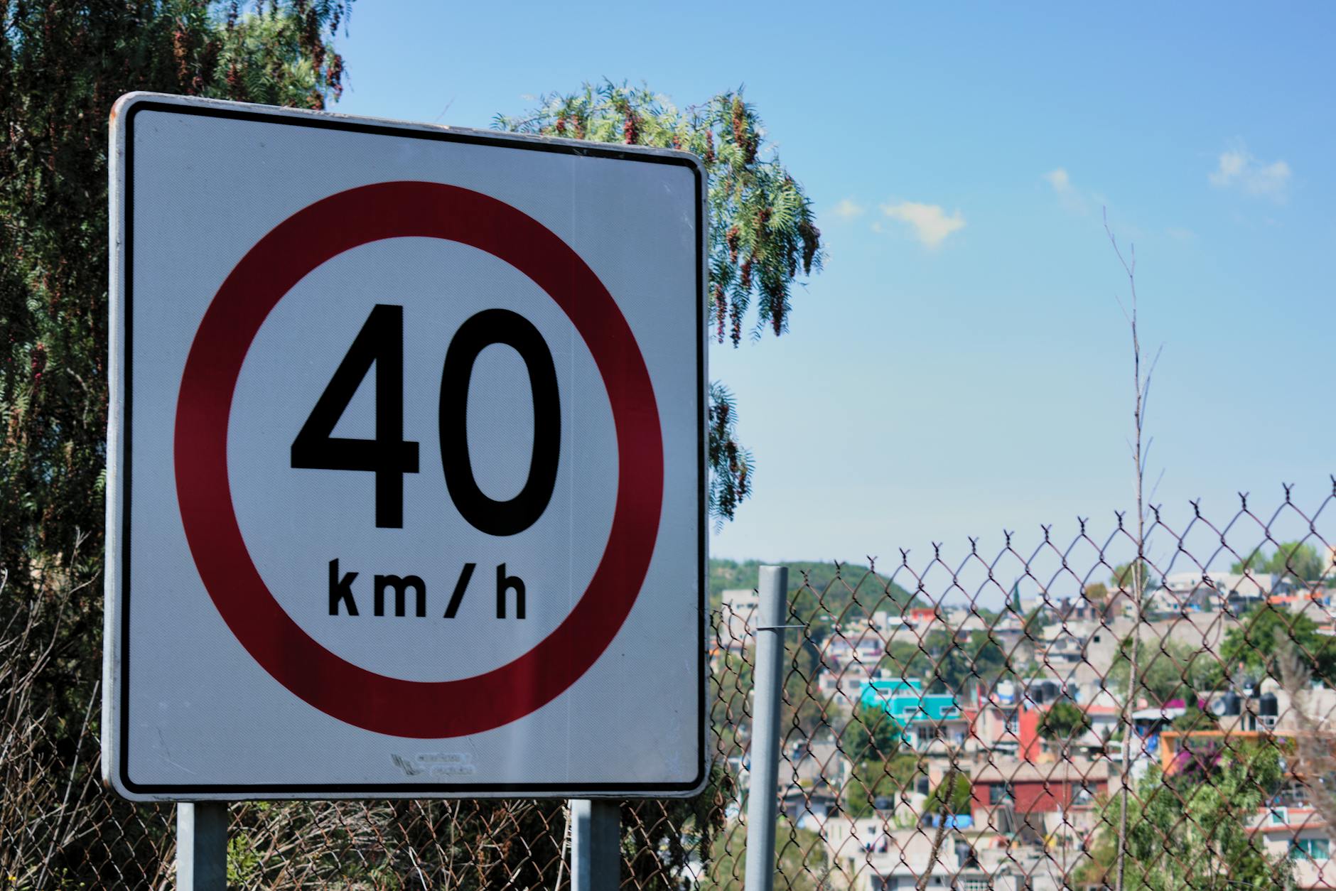 Znak ograniczenia prędkości do 40 km/h przy ogrodzeniu w mieście