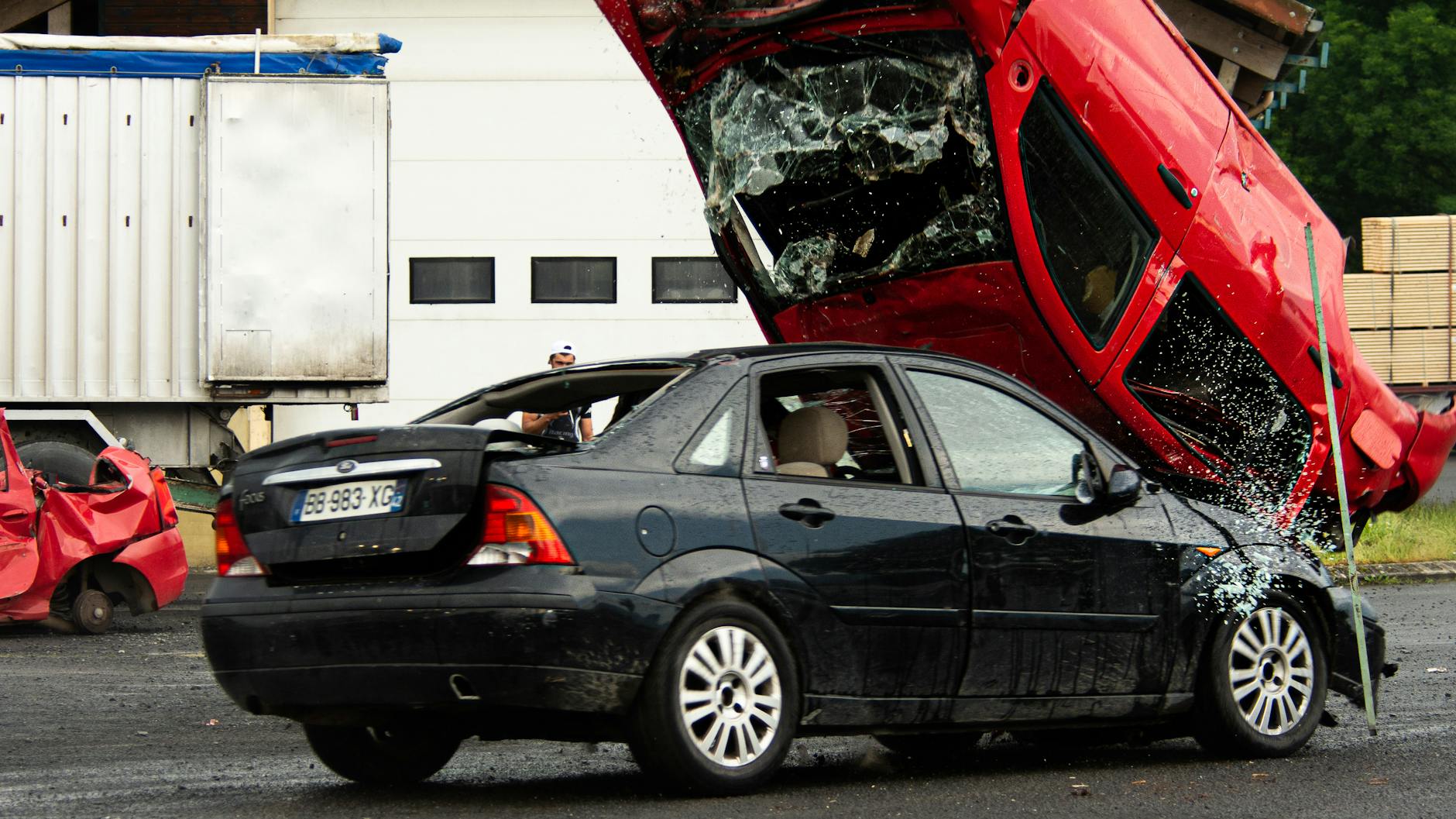 Czerwony samochód przewrócony na czarne auto po zderzeniu na drodze