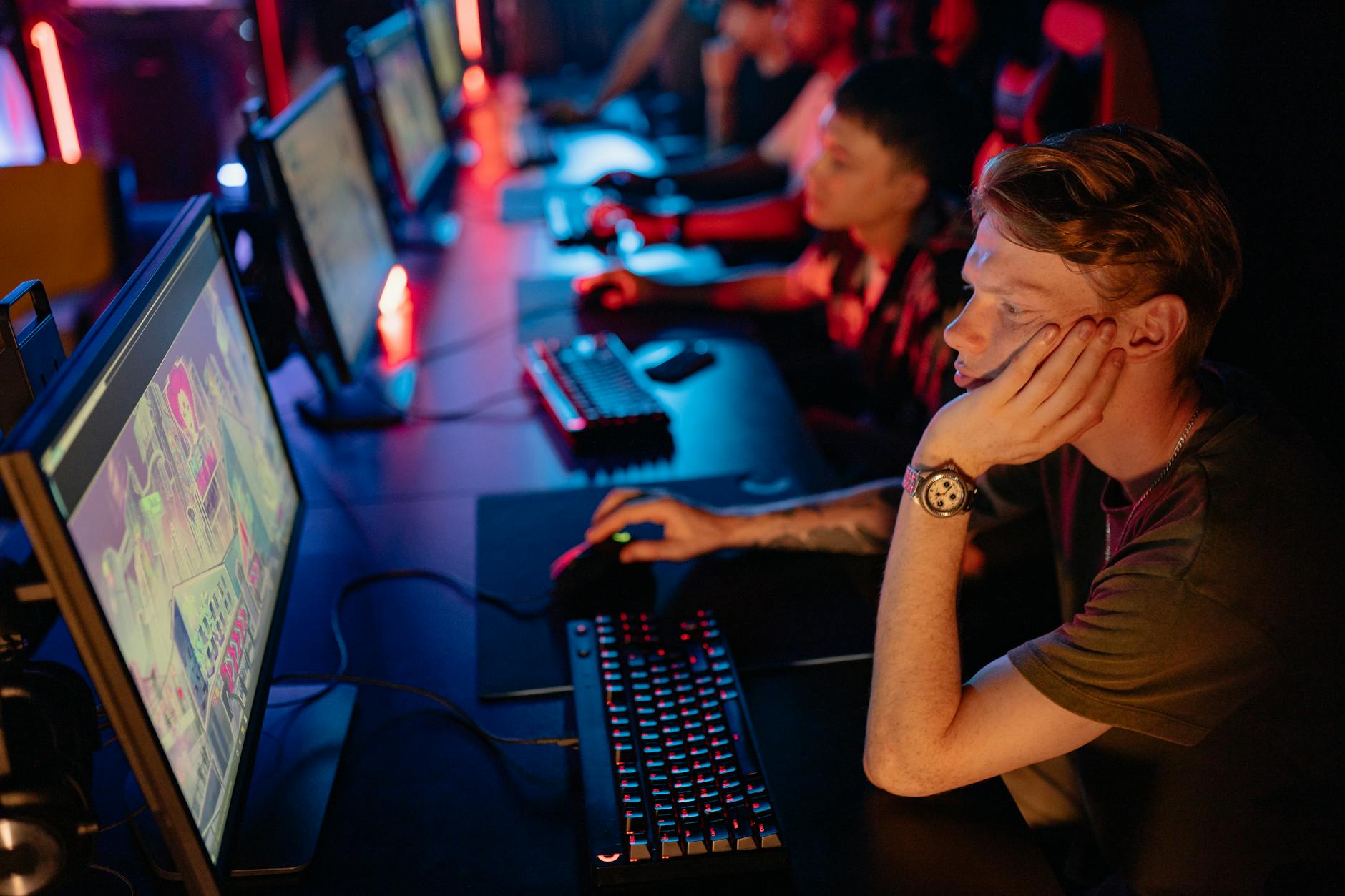 Gracze e-sportowi przy komputerach podczas turnieju w ciemnej hali