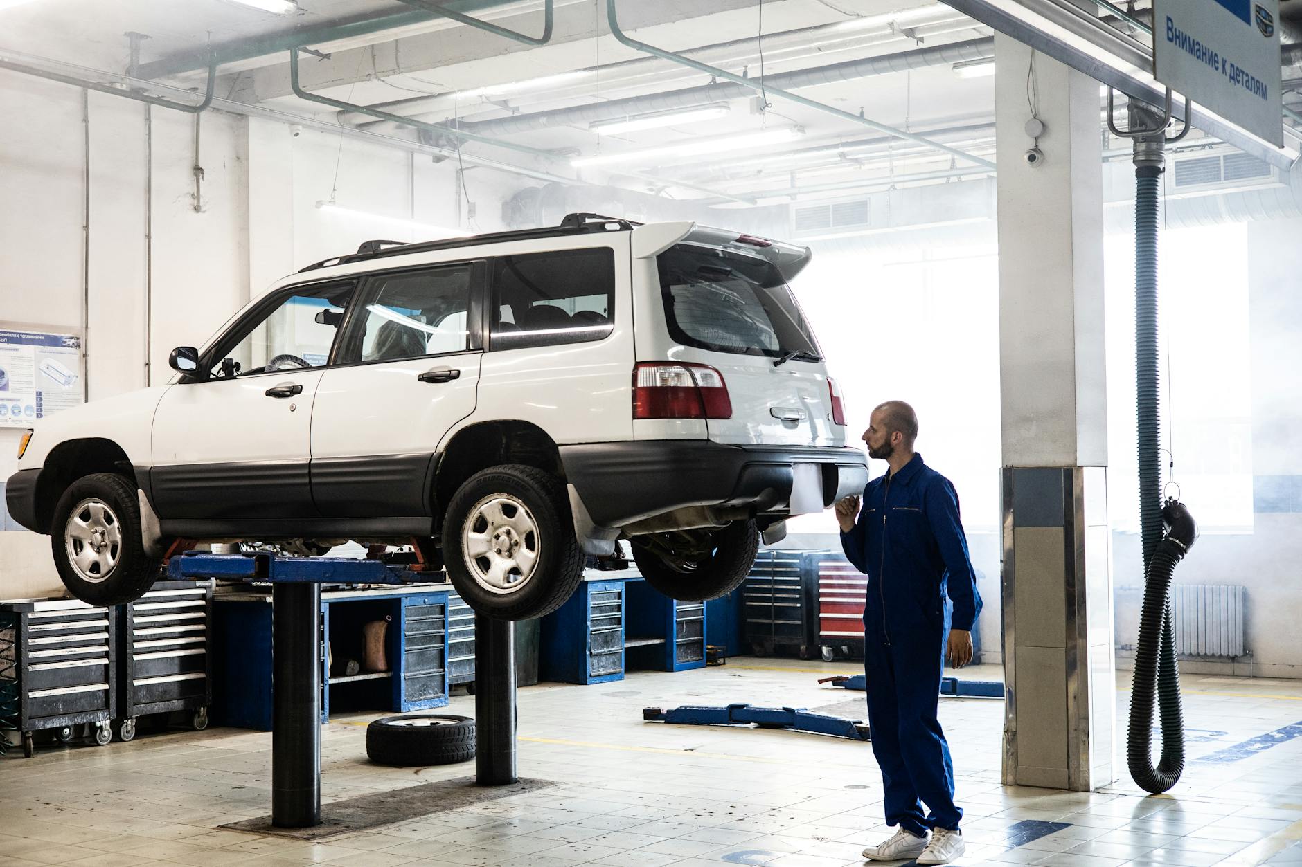 Mechanik ogląda podniesionego SUV-a w nowoczesnym warsztacie Mechanik ogląda podniesionego SUV-a w nowoczesnym warsztacie