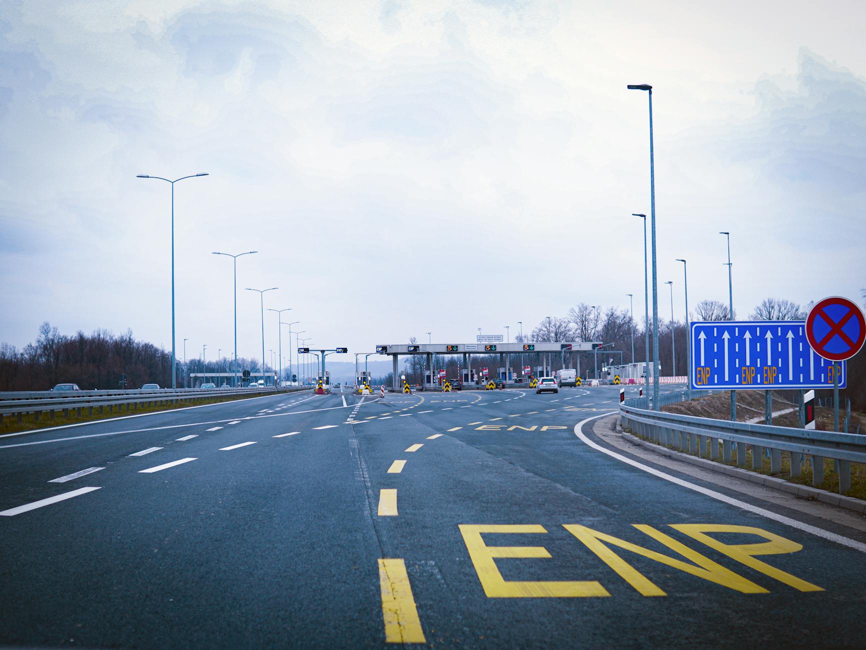 Pusta autostrada prowadząca do bramek opłat drogowych pod pochmurnym niebem