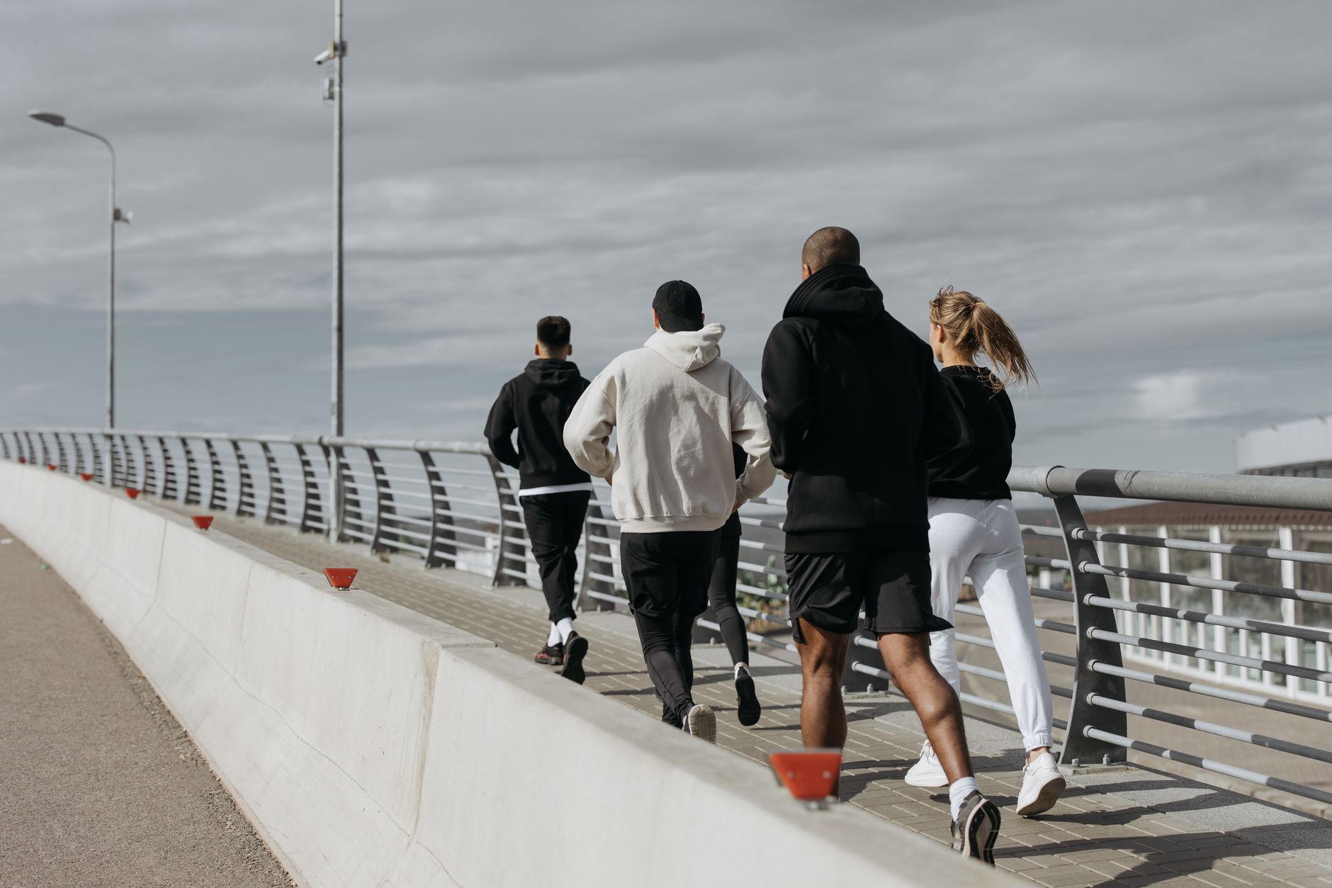 Grupa dorosłych biegaczy jogginguje razem po miejskim moście