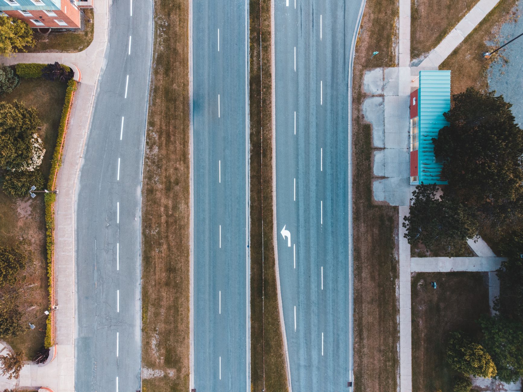 Pusta dwupasmowa ulica z zatoką autobusową i zielenią z lotu ptaka