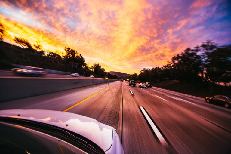 Rozmyte samochody pędzące autostradą o zachodzie słońca